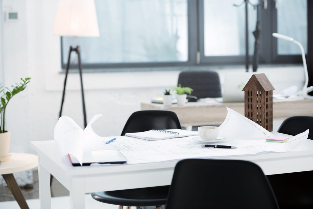 modern office workplace with blueprints and papers on desk